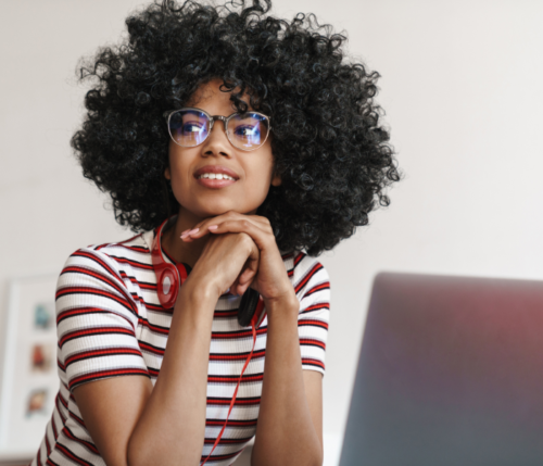Joven afroamericana con anteojos con filtro de luz azul pensativa mirando al infinito